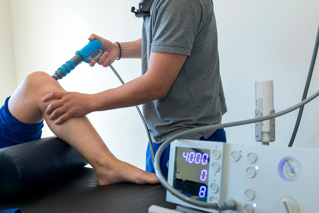 Health professional doing shockwave therapy in knee