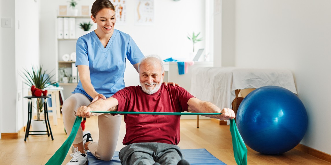 Doctor or nurse caregiver exercise with senior man at clinic or nursing home