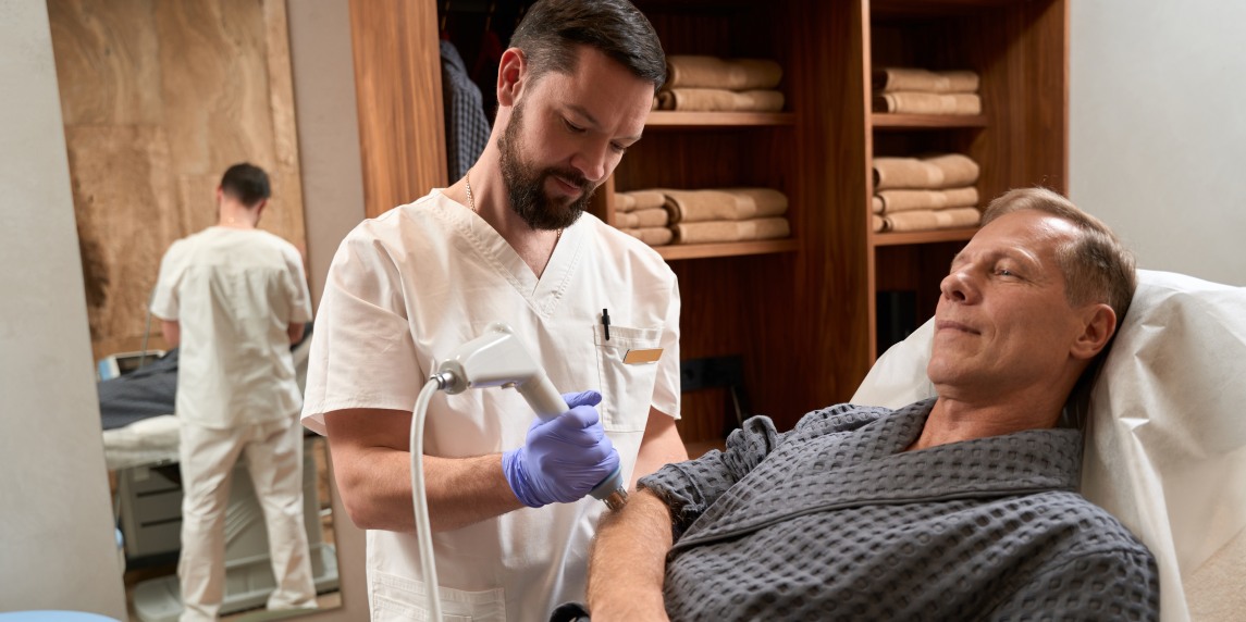 Qualified doctor having a shockwave therapy session with his patientv