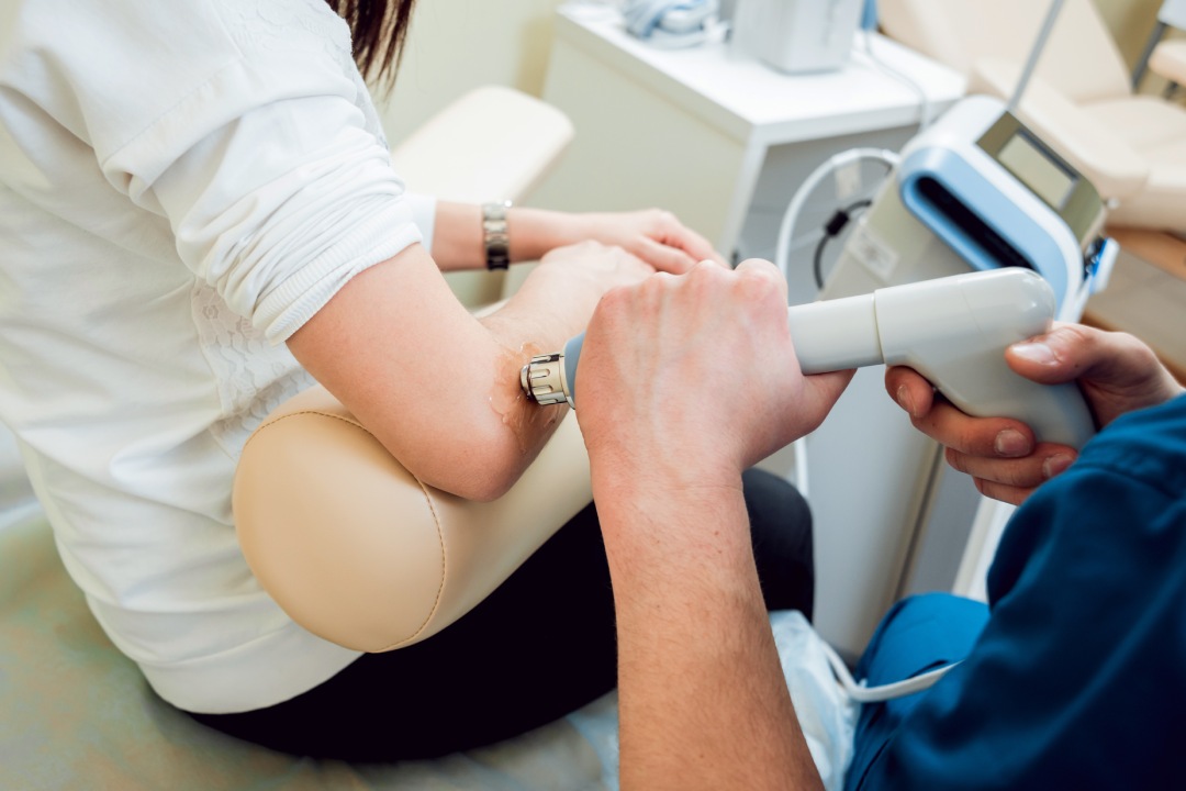 Shock wave therapy. The magnetic field, rehabilitation. Physiotherapist doctor performs surgery on a patient's elbow