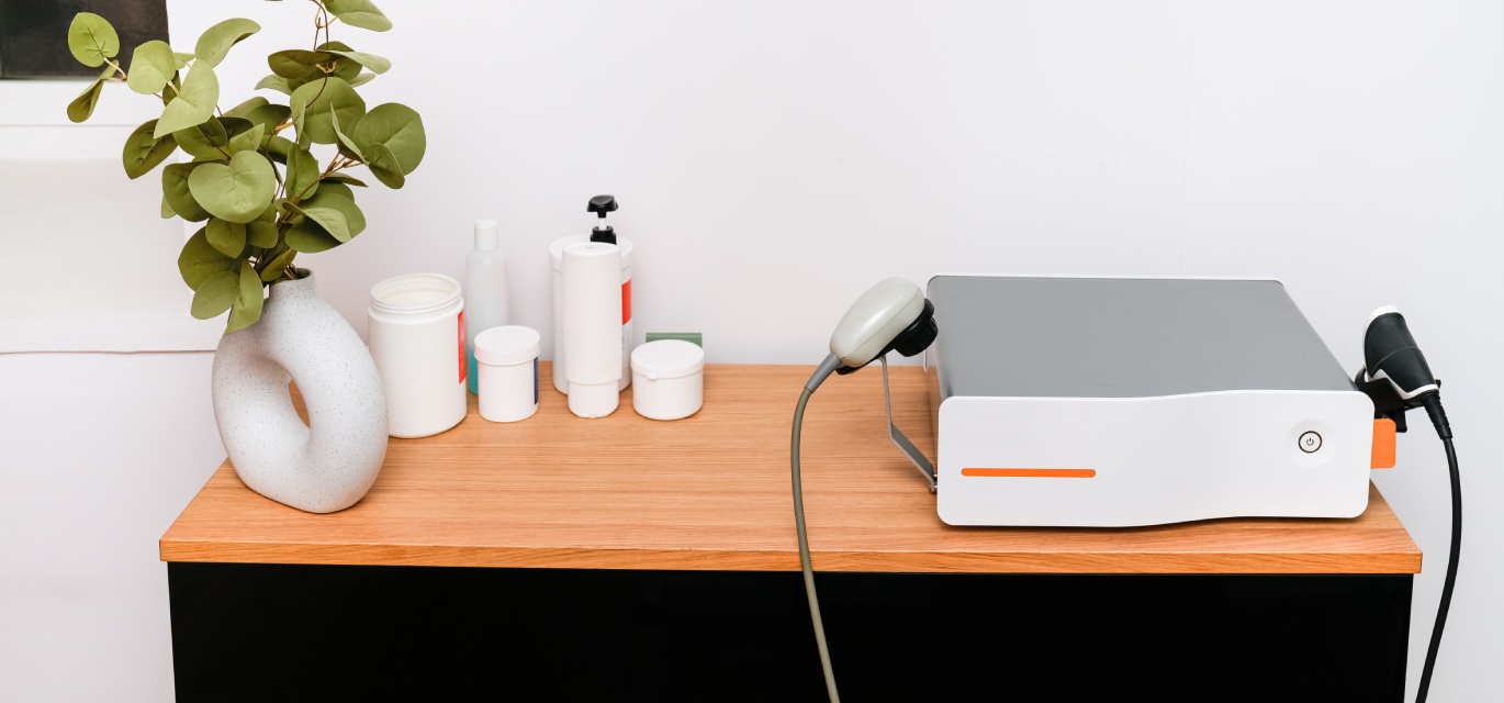 Interior of a physiotherapy clinic featuring a shockwave therapy machine and calm decor.